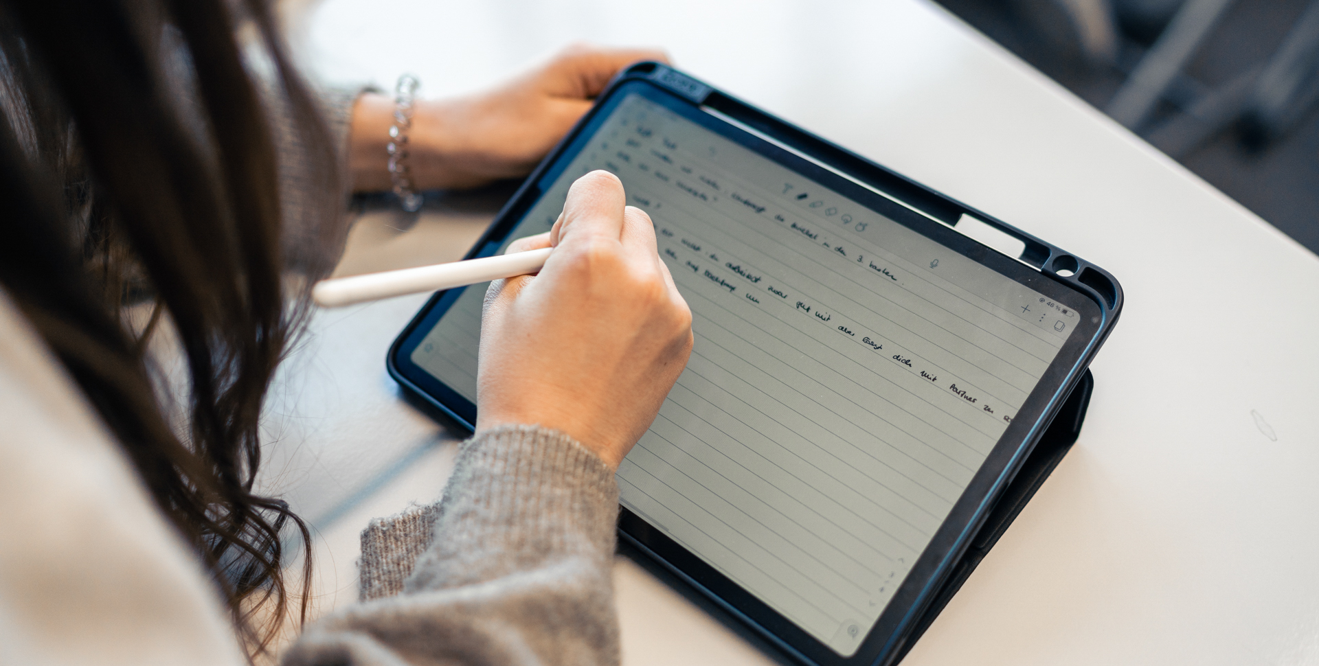 Eine Person schreibt mit einem Stylus auf einem Tablet, das Notizen anzeigt.