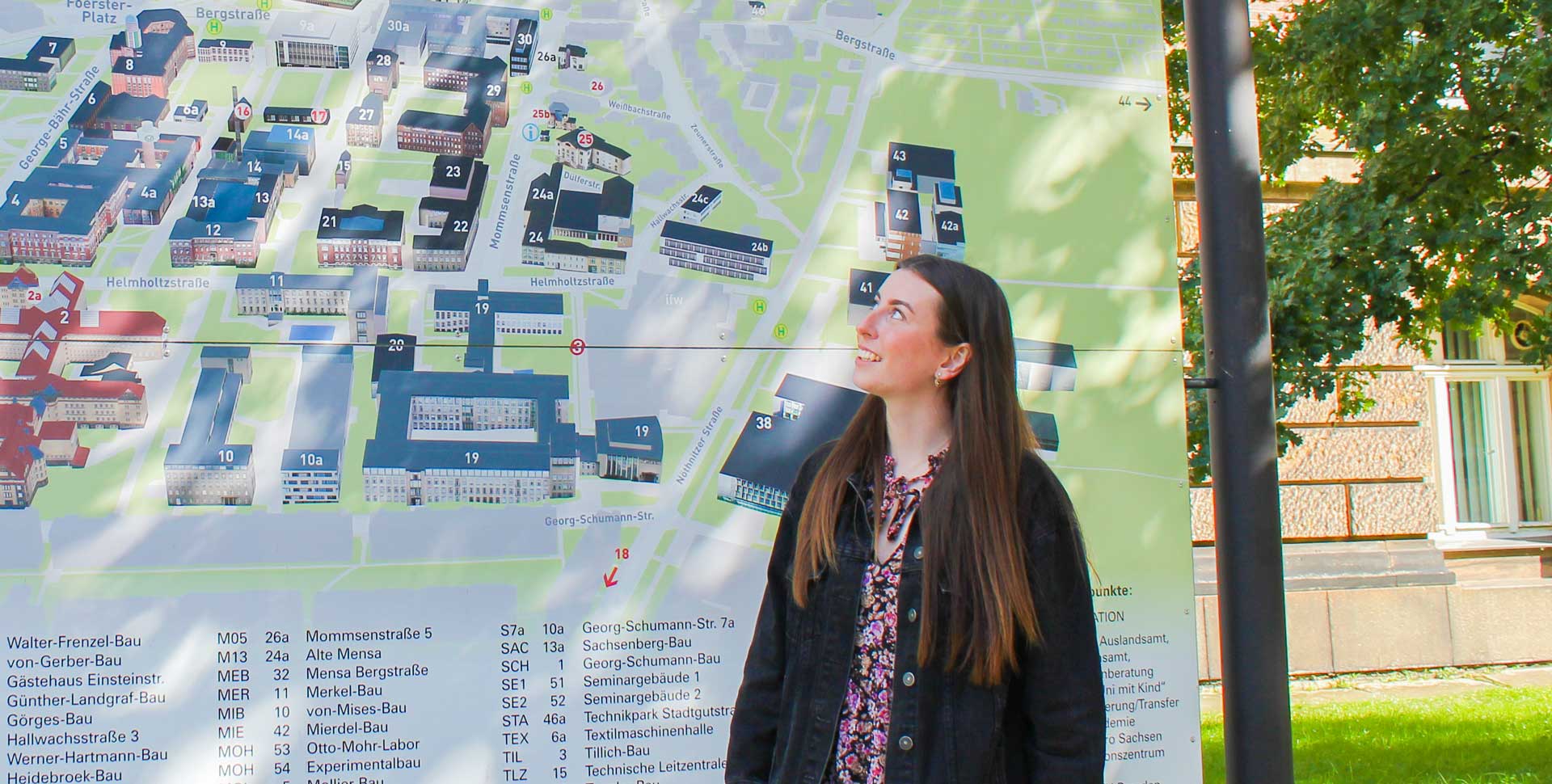 Eine Studentin schaut auf einen Campusplan der Technischen Universität Dresden.