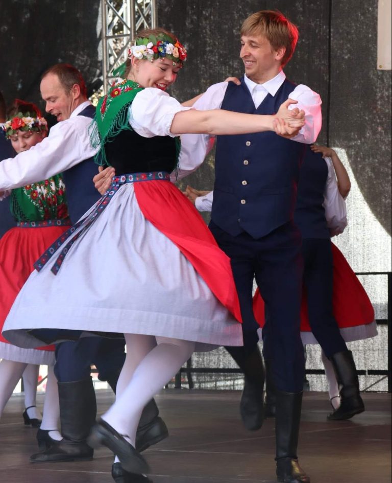 Zwei Personen in traditioneller Tracht tanzen auf einer Bühne während einer Aufführung.