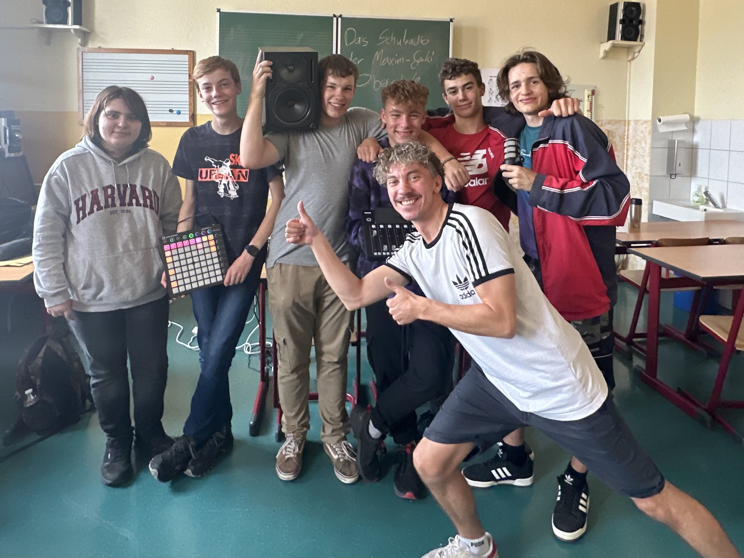 Gruppe von Schülern und einem Lehrer in einem Klassenzimmer mit Musikgeräten für das Schulradio.