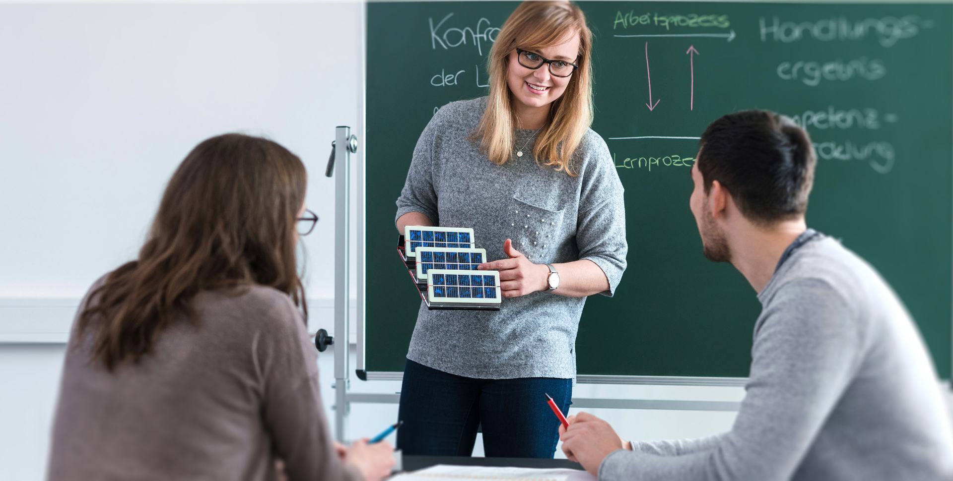 Lehrerin zeigt Schülern Solarzellen während des Unterrichts in einem Klassenzimmer.
