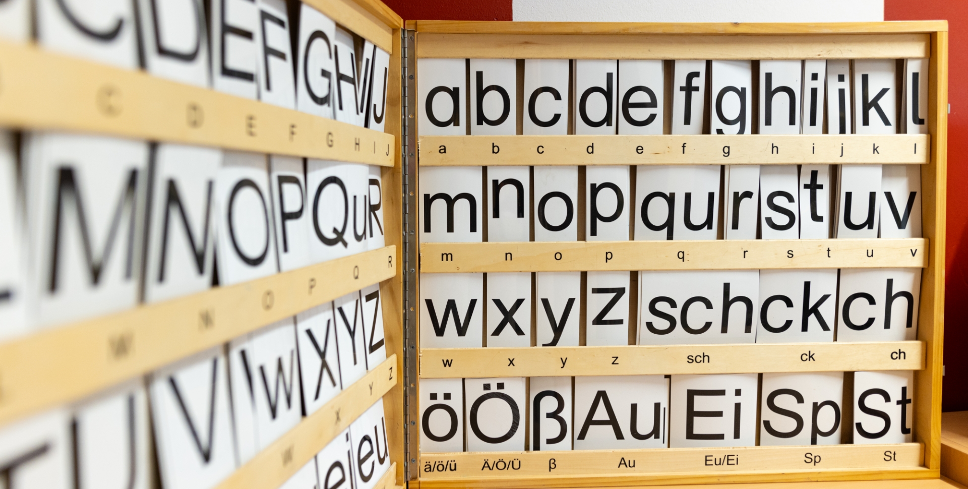 Holztafel mit alphabetischen Buchstaben in Groß- und Kleinbuchstaben angeordnet.